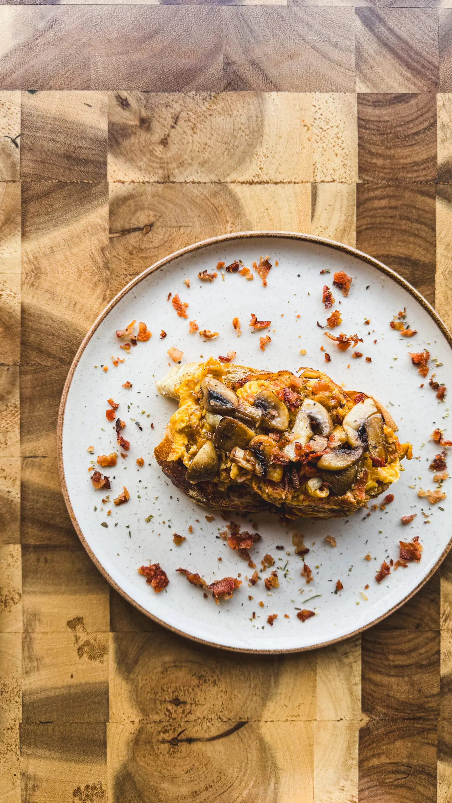 Toast topped with roasted vegetables and nuts on a white plate.