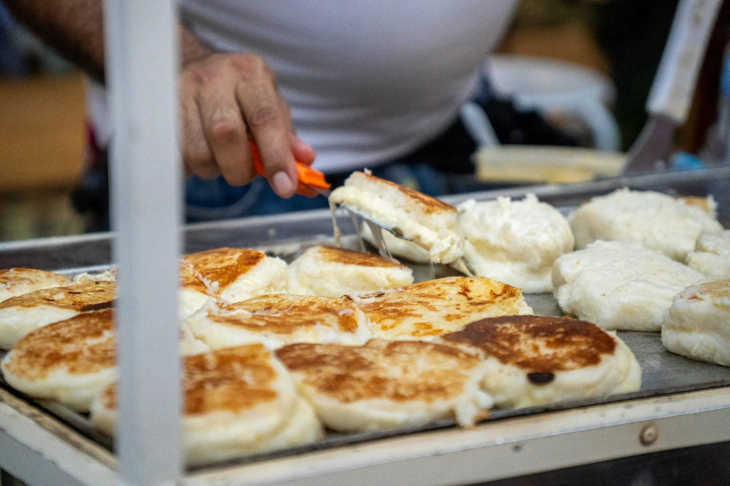 a white arepa being cooked on a black grill