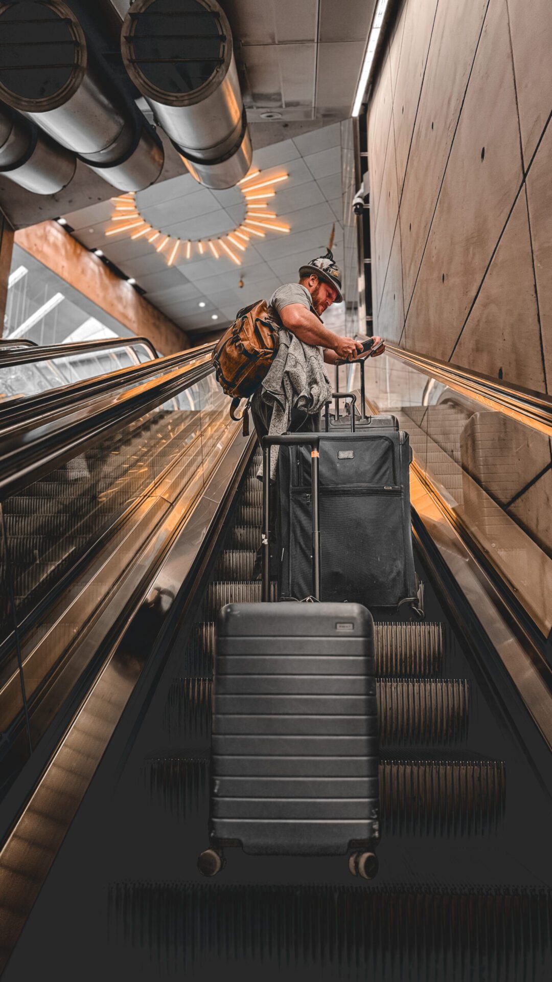 Man standing on escalator in train station with luggages