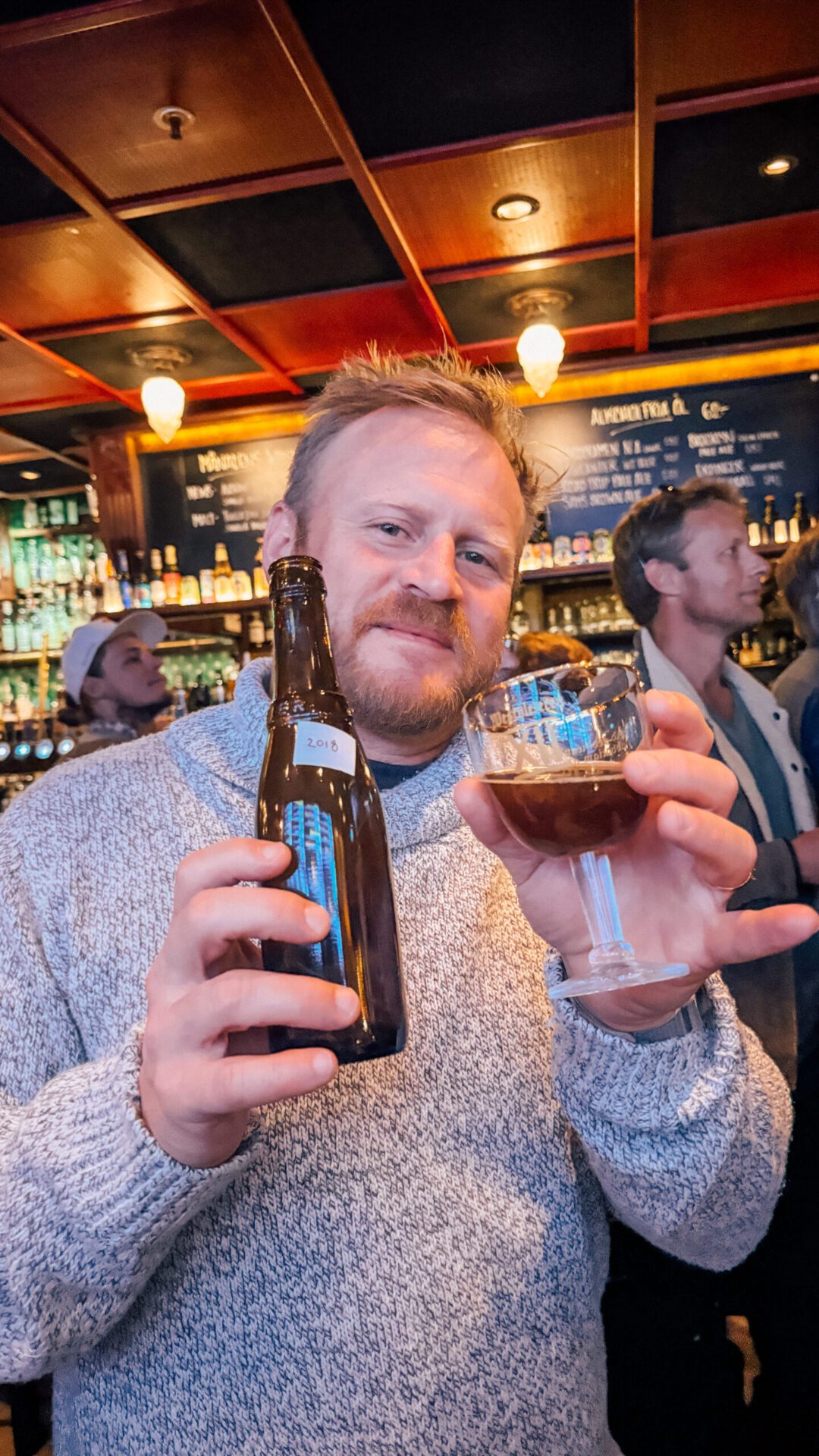 Man holding up a lableless beer bottle and a glass
