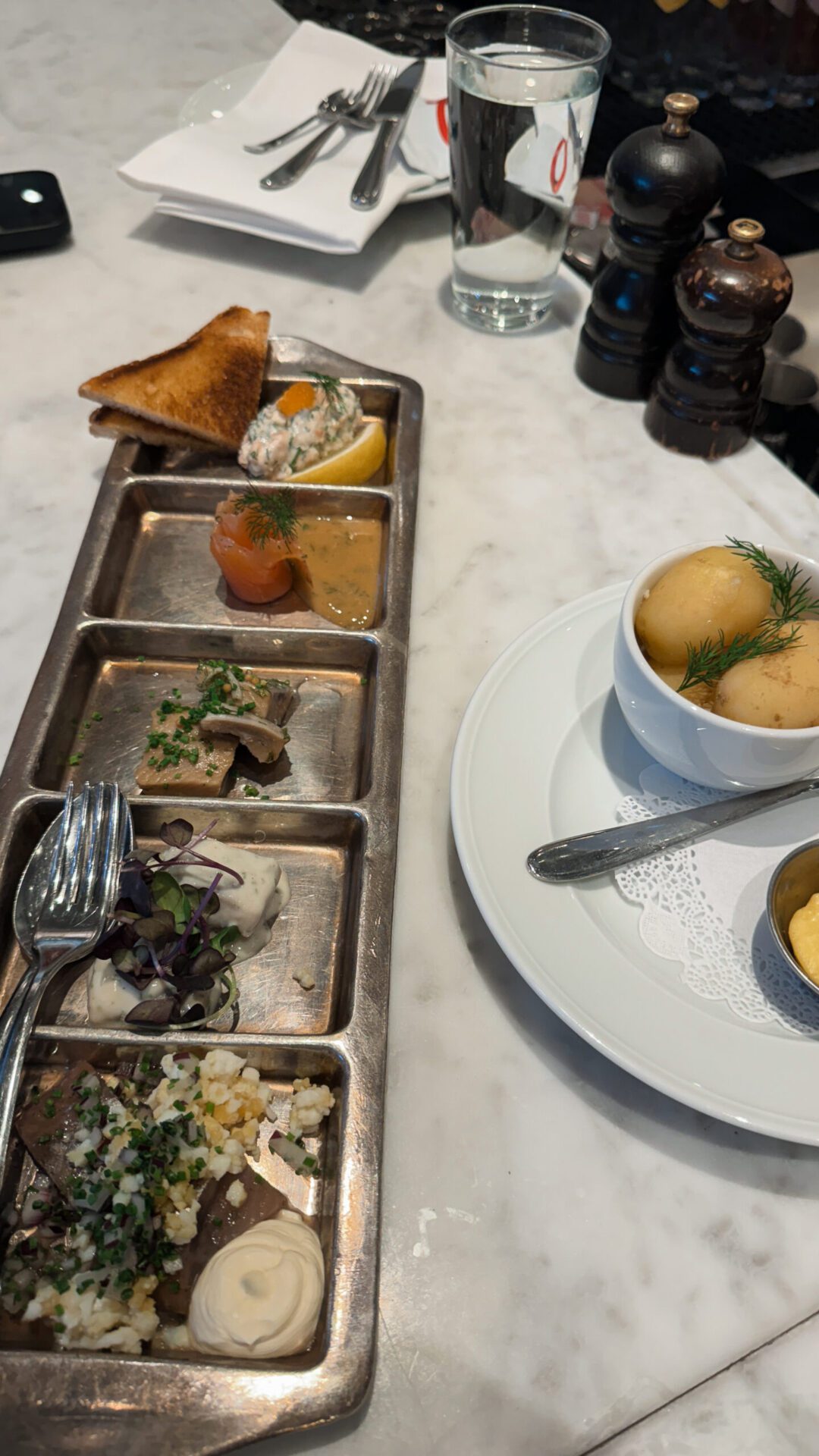 Sampler of herring preparations served with crispbread, new potatoes, and whipped butter.