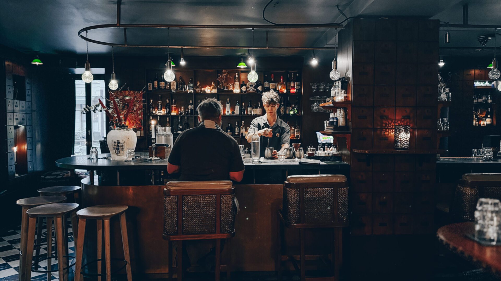 Man sitting at a bar being served by a bartender