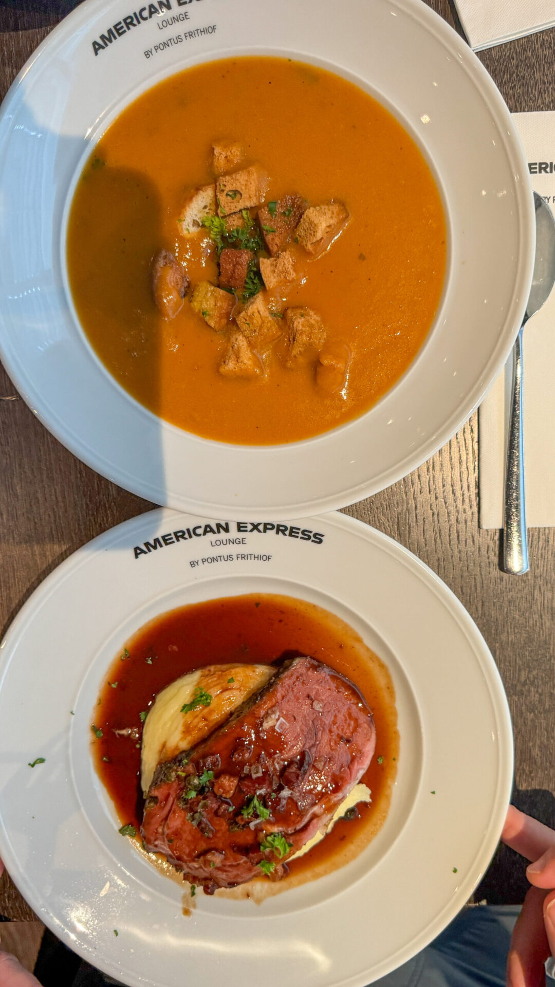 Two bowls - one with orange soup and the other with a meat dish with potatoes