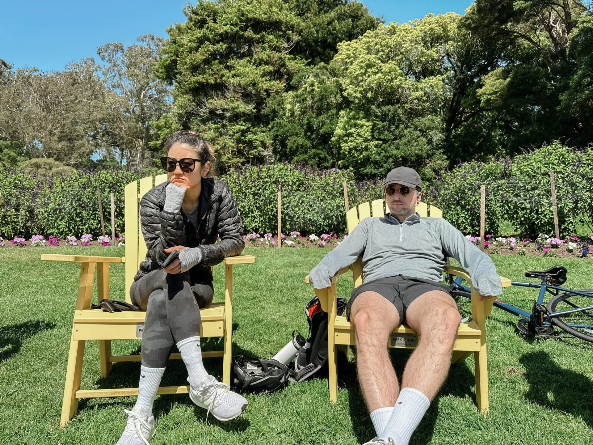 Two people relaxing on a green bench in Golden Gate Park