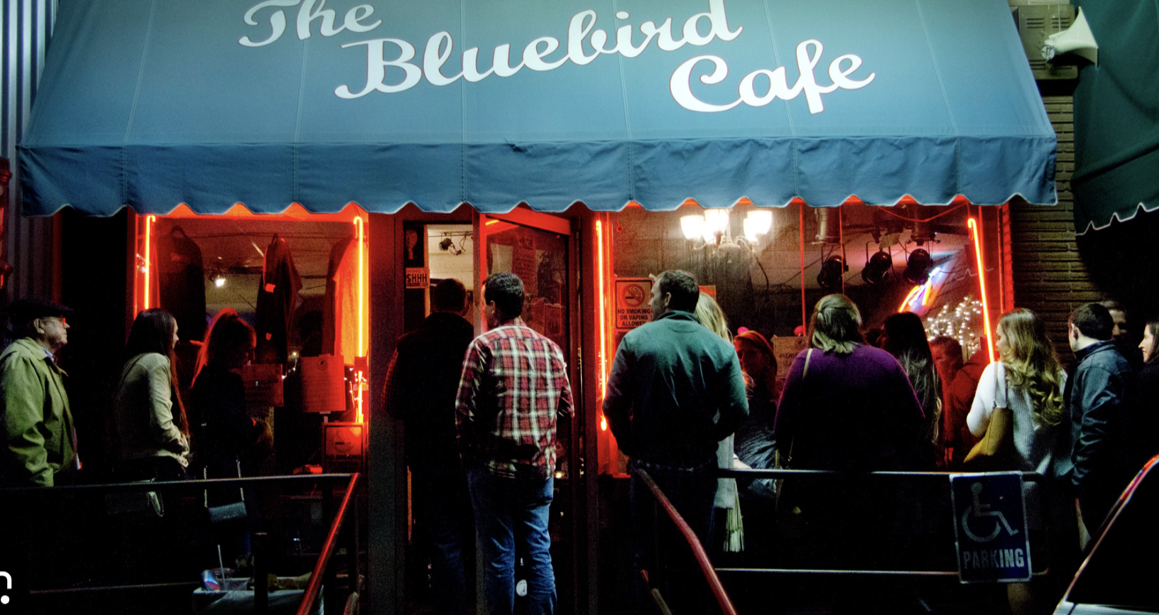 woman with a bob haircut holding a camera up to her face with a light in the background