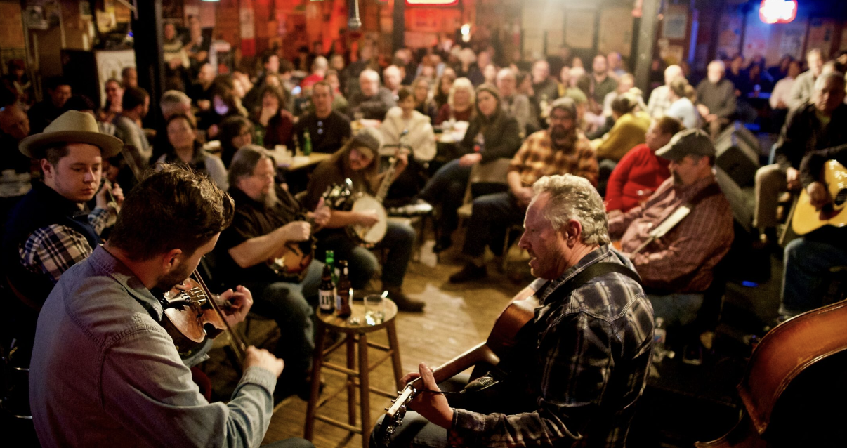 woman with a bob haircut holding a camera up to her face with a light in the background