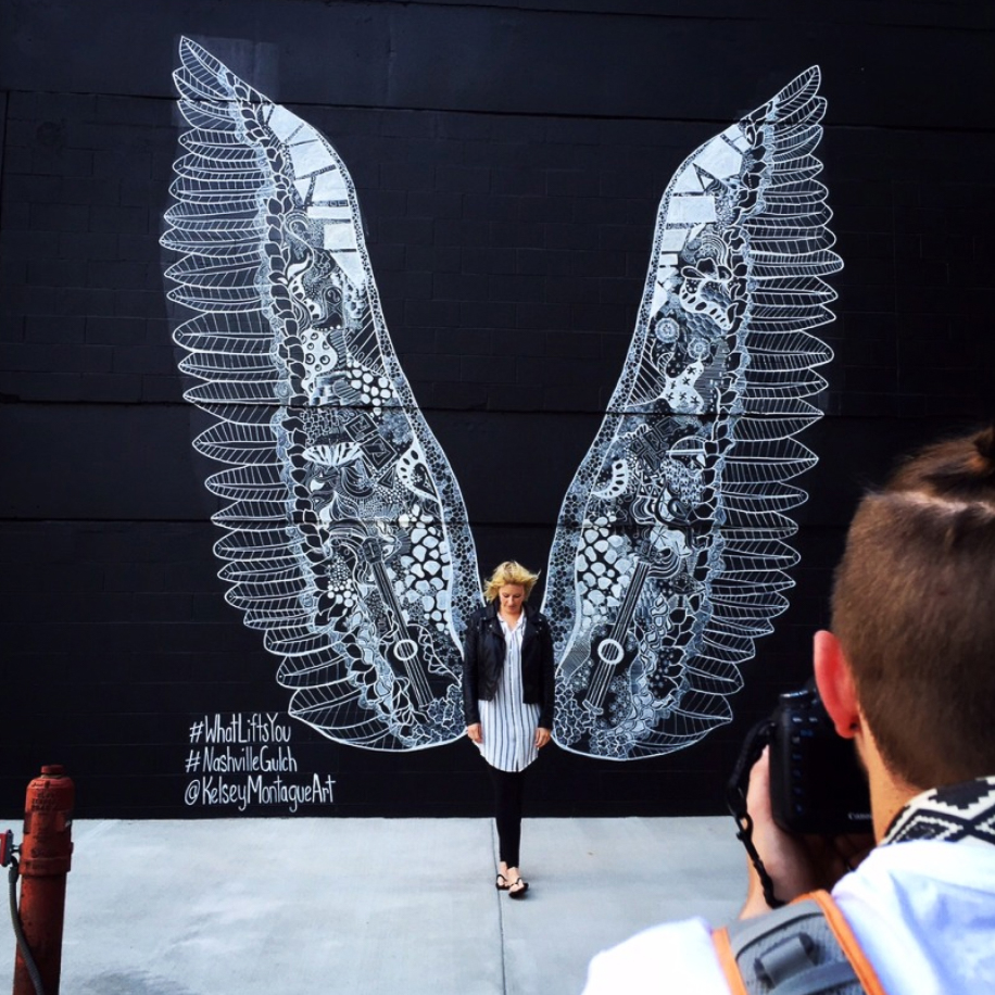 woman with a bob haircut holding a camera up to her face with a light in the background