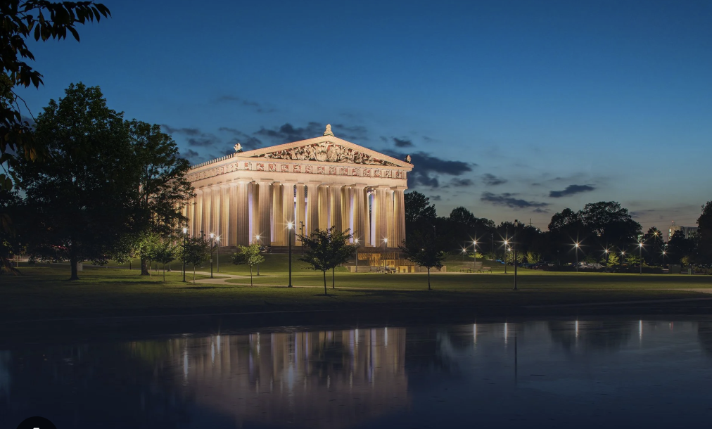 woman with a bob haircut holding a camera up to her face with a light in the background
